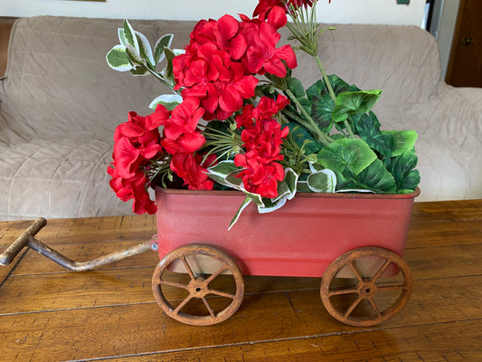 Red rustic wagon with artificial red flowers in it