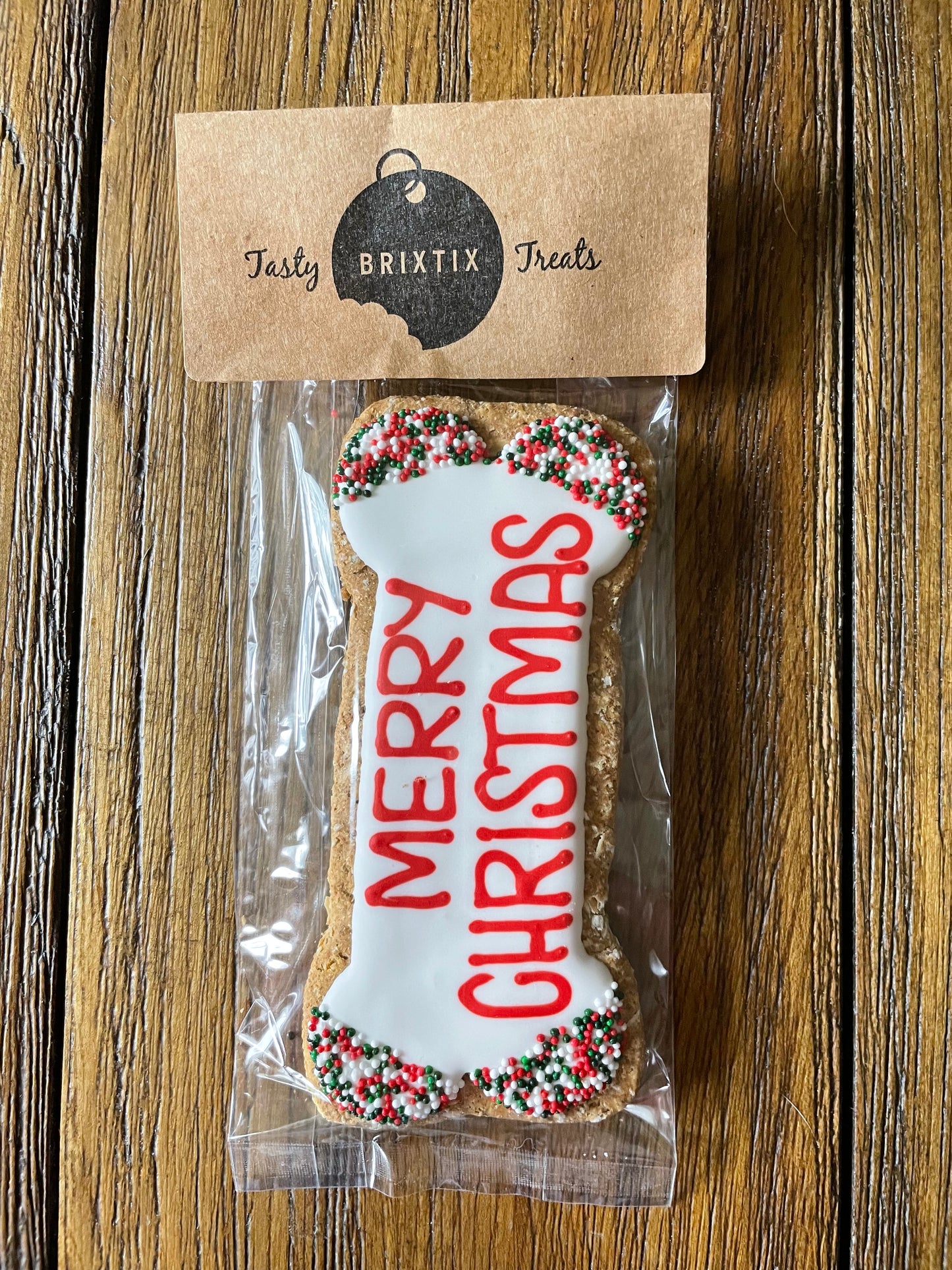 Bone shaped dog biscuit that says MERRY CHRISTMAS in red letters.